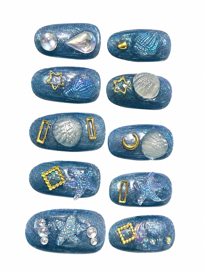長女が作った「海」がテーマのネイルチップ10本。青いラメのベースに貝殻、ヒトデ、月、パール、ゴールドの縁取りがデコレーションされている